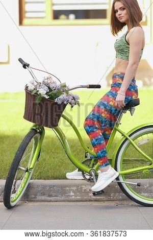 The Girl In Leggings And Top Engaged In Sports Cycling. Spring. The Girl Is Resting And Riding A Bic