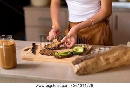 Woman Making Avocado Peanut Butter Toast For A Healthy Breakfast At Home