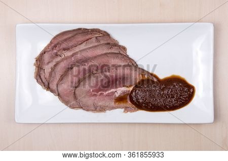 Roast Beef With Tomato Sauce On A White Plate.