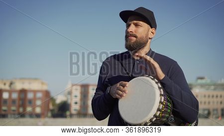 A Street Musician Plays Tom-tom On A Drum. A Musician Stands On The Street And Holds A Drum Tomtom I