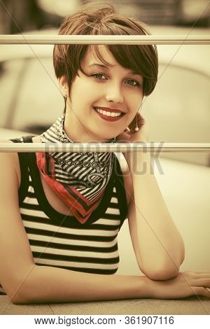 Happy young fashion woman with pixie hair on city street Stylish female model in striped tank top and silk scarf