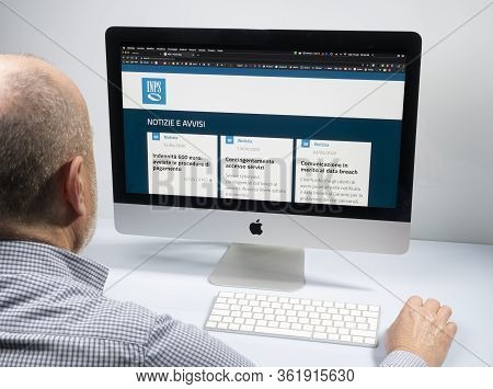 A Man Sitting In Front Of The Computer While Looking At The Site Of The Italian National Social Secu