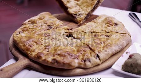 Close Up Of Person Picking Up A Slice Of Traditional Georgian Dish Kubdari.  Flatbread Stuffed With 