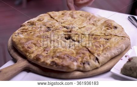Close Up Of Person Picking Up A Slice Of Traditional Georgian Dish Kubdari.  Flatbread Stuffed With 