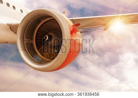 3d Rendering Of Airplane With Red Engine In Flight Through Sunset Or Sunrise Clouds With Lens Flare 