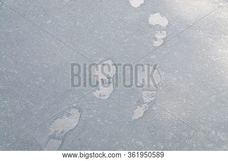 Close Up Of Wet Footprints On A Road Covered With Sleet