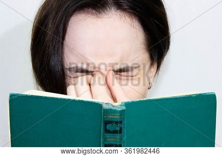 A Large Portrait Of A Beautiful Girl With An Old Book, Closed Her Tired Eyes From Reading. Close-up 