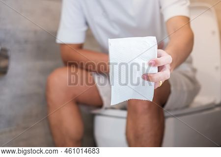 Man Holding Toilet Paper Roll During Sit On Toilet Bowl. Diarrhea, Constipated Period, Infection, Ab