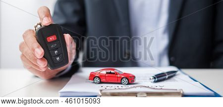 Businessman Hand Holding Remote Keyless With Car Toy, Pen And Contract Document. Buy And Sale, Insur