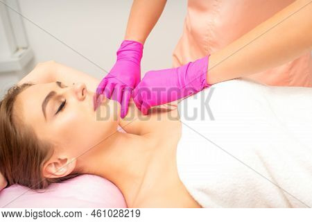 Waxing. Depilation Under The Armpits Of The Young Woman Lying With Closed Eyes In The Spa Salon