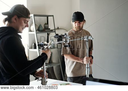 Young Assistant Helping Photographer Or Videographer Adjust Steadicam