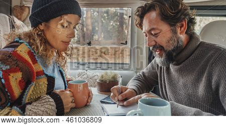 Couple Plan Travel Destination From Inside A Camper Van. Man And Woman Indoor Leisure Activity Toget