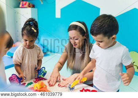 Relaxing Sensory Play With Moldable Kinetic Sand At Nursery School. Toddlers With Their Teacher Havi