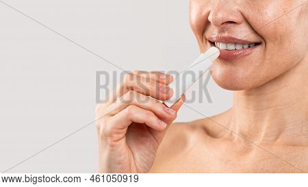 Lips Care. Smiling Middle Aged Woman Applying Lip Balm, Closeup Shot