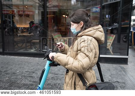 Brussels Belgium - 01.31.2022 A Young Woman In A Warm Down Jacket And A Mask