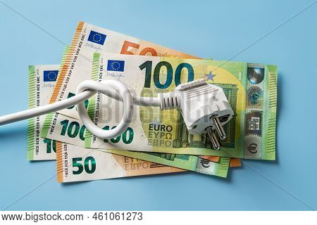 Knotted Power Cable With Electric Plug On 50 And 100 Euro Banknotes Over Blue Background. Concept Of