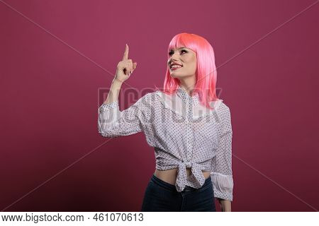Portrait Of Beautiful Person With Pink Hair Using Index Finger To Point Up, Indicating Upwards Direc