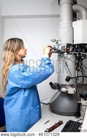 Young Female Scientist Loading A Specimen Using A Sample Holder Into A Transmission Electron Microsc