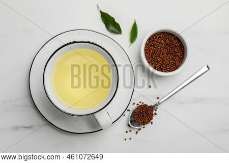 Cup Of Buckwheat Tea And Granules On White Marble Table, Flat Lay