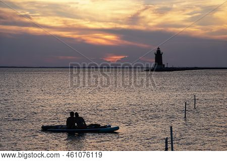 Silhouette Of A Couple Enjoying Sunset From A Kayak At Cape Henlopen State Park, Lewes, Delaware, U.
