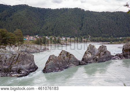 A Fast-flowing Wide And Full-flowing Mountain River. Large Rocks Stick Out Of The Water. Big Mountai