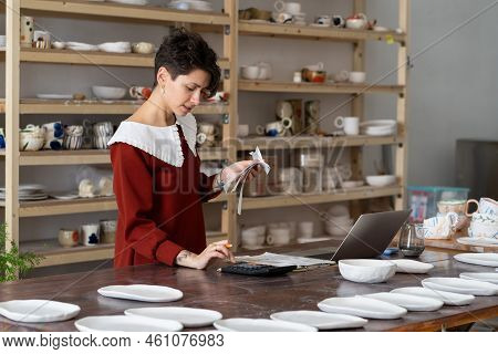 Young Busy Focused Woman Entrepreneur Doing Paperwork, Female Artisan Ceramics Shop Owner Holding Re