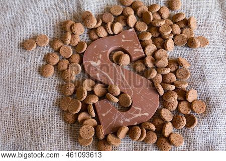 Dutch Sinterklaas Tradition: A Chocolate Letter And Candy Called Pepernoten On A Jute Background.