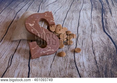 Dutch Sinterklaas Tradition: A Chocolate Letter And A Bag With Candy Called Pepernoten On A Old Wood