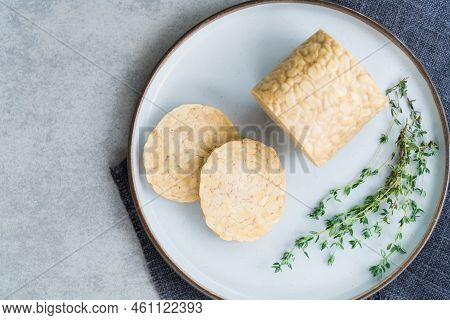 Top View Raw Tempeh Or Tempeh, Made Of Fermented Soybean Seeds. Tempeh Slices On Plate With Herbs. S