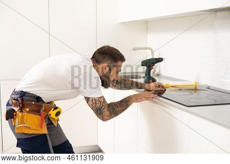 Craftsman Installs Hob In Kitchen. Household Appliance Installation Services Concept