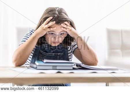 Schoolgirl In Glasses Tries To Comprehend Study Materials Holding Her Head By Both Hands.