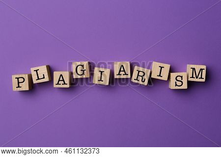 Word Plagiarism Made Of Wooden Cubes On Violet Background, Top View
