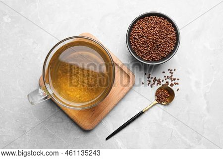 Cup Of Aromatic Buckwheat Tea And Granules On Light Marble Table, Flat Lay