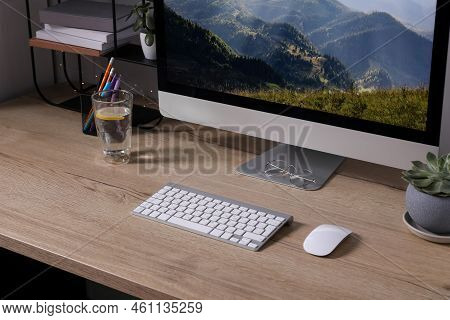 Modern Computer And Glass Of Lemon Water On Wooden Table Indoors
