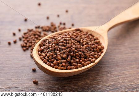 Spoon With Buckwheat Tea Granules On Wooden Table, Closeup