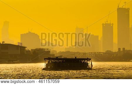 A Boat Carrying People Crossing The Chao Phraya River In The Morning. Behind It Is The Buddha Yodfa 