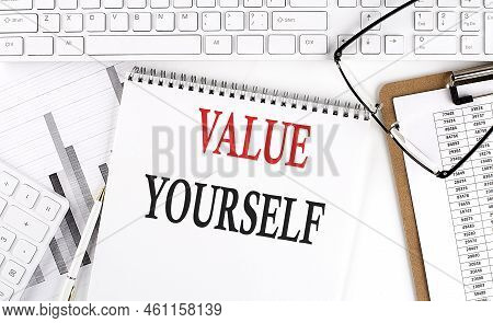 Text Value Yourself On Office Desk Table With Keyboard, Notepad And Analysis Chart On A White Backgr