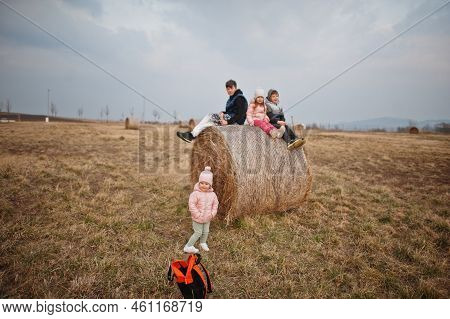 Four Kids Sitting On Haycock At Field.