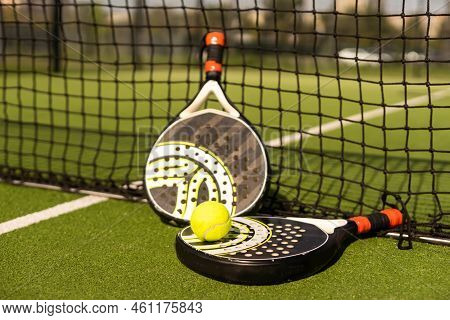 Yellow Balls On Grass Turf Near Padel Tennis Racket Behind Net In Green Court Outdoors With Natural 