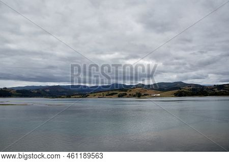 Sea Of Gray Tones Under A Cloudy Sky With Mountains In The Background. Copyspace. Horizontal Photogr