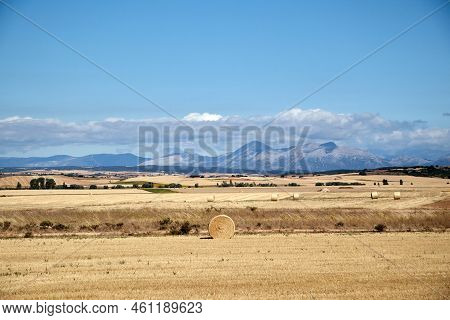 Landscape Of A Straw Field With Mountains In The Background In Which A Straw Roll Appears In The For