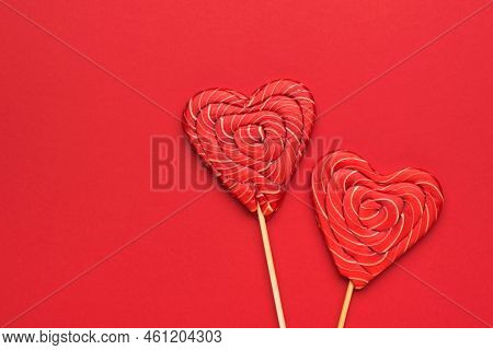 Two Large Red Heart-shaped Candies On A Stick On A Red Background. Minimal Concept Of Sweet Life And