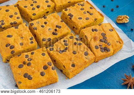 Pumpkin Blondie Or Cake With Chocolate Drops, Walnuts, Cinnamon And Anise On Baking Paper On A Blue 