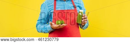 Man Crop View In Red Apron Holding Limes And Juice Bottle Yellow Background, Juicery