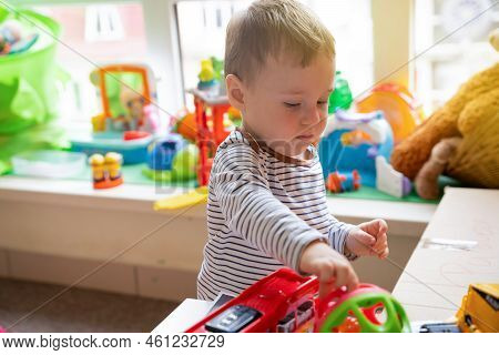 Toddler Boy Plays With Toys In The Children's Room. Educational Toys For Young Children. Child One A