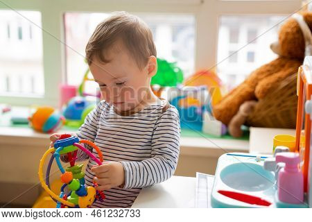 Toddler Boy Plays With Educational Toys In The Children's Room. The Study Of Colors And The Developm