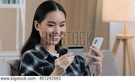 Smiling Asian Ethnic Woman Customer User Holding Bank Credit Card With Virtual Money Typing Smartpho