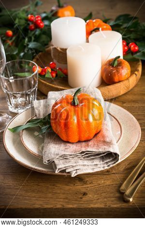 Autumn Table Setting With Plate, Pumpkin And Candles At Wooden Table. Thanksgiving Food Concept.
