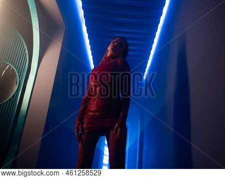 A Fashionable Photo Shoot With Tinted Blue, A Young Beautiful Model In A Scarlet Dress, In A Mysteri
