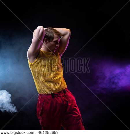 A Young Muscular Man In A Bright Outfit Poses In A Pretentious Pose, Style And Grotesque. Attractive